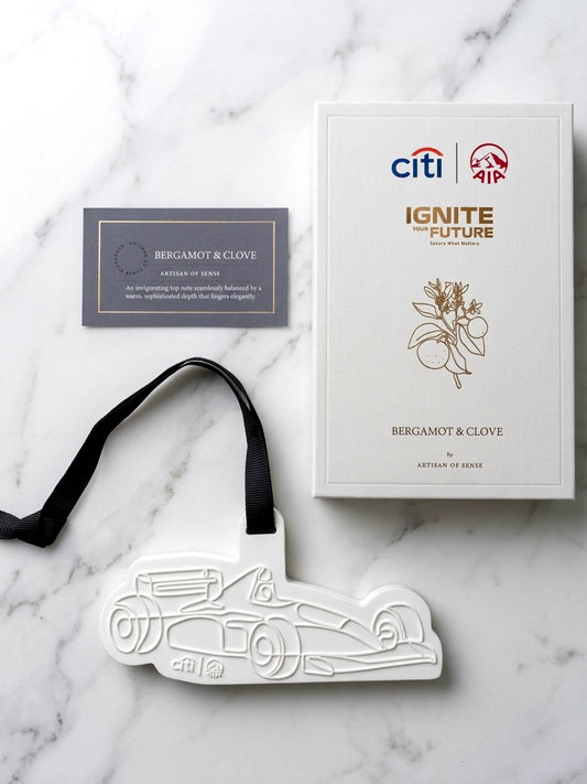 Bespoke AIA custom debossed race car clay aroma diffuser hanging ornament displayed alongside a Bergamot & Clove fragrance note card and rigid gift packaging box on white marble, designed for VIP corporate client gifting by Artisan of Sense Singapore.