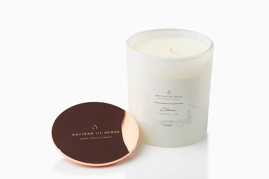 The warm glow of a handcrafted Bergamot & Clove soy candle. It sits elegantly in a glass jar, in sustainable packaging perfect for a unique gift.
