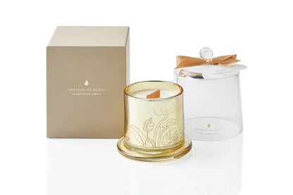 Observe the inviting flame of a soy candle with a crackling FSC wood wick, elegantly presented in a gold glass jar with a glass cloche. Its sustainable packaging underscores its suitability as a unique gift. Scent: Musk . Bergamot . Rose